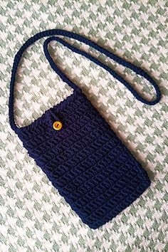 a small blue purse sitting on top of a white and green blanket with a yellow button