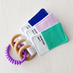 three different colored rubber rings on top of each other next to a cloth holder with two wooden rings in the middle