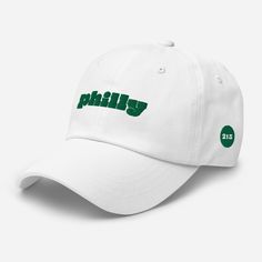 "Philly 215 Embroidered Hat, Philadelphia White Dad Hat, Philly Baseball Cap, Philly Sports Hat You'll be head over heels with this timeless piece! The hat comes in various colors to match your style and sits on your head just like a crown, thanks to the adjustable strap. * 100% chino cotton twill * Green Camo color is 35% chino cotton twill, 65% polyester * Unstructured, 6-panel, low-profile * 6 embroidered eyelets * 3 ⅛\" (7.6 cm) crown * Adjustable strap with antique buckle * Blank product sourced from Vietnam or Bangladesh This product is made especially for you as soon as you place an order, which is why it takes us a bit longer to deliver it to you. Making products on demand instead of in bulk helps reduce overproduction, so thank you for making thoughtful purchasing decisions!" Sporty Hat With Letter Print And Curved Brim, Sporty Curved Brim Hat With Letter Print, Trendy Visor Hats For Sports Events, Trendy Curved Brim Hat For Sports Events, Trendy Curved Bill Hat For Sports Events, White Dad Hat, Philly Sports, Sports Hat, Embroidered Hat