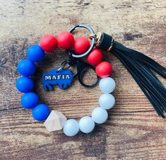 a bracelet with an elephant charm and tassel on top of a wooden table next to a keychain