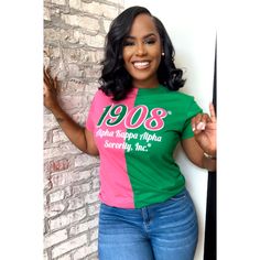 a woman wearing a pink and green shirt with the year 1908 printed on it, leaning against a brick wall