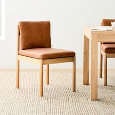 a brown chair sitting next to a wooden table on top of a carpeted floor