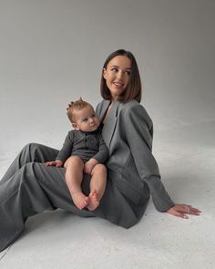 a woman sitting on the ground holding a baby