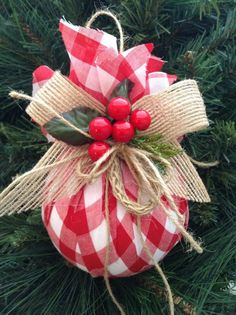 a red and white ornament hanging from a christmas tree with berries on it