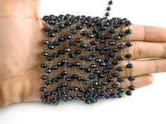 a hand is holding a black beaded chain