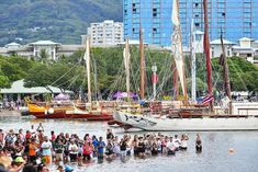 many people are standing in the water near boats