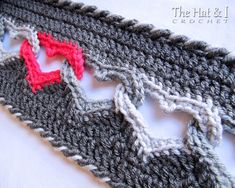 a crocheted piece of cloth with red and gray stitchs on top of it