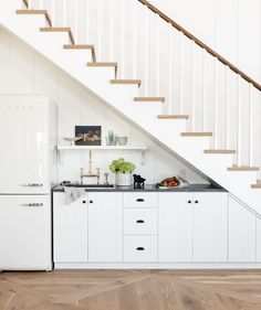 a kitchen with white cabinets and wooden stairs