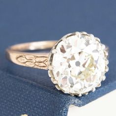 A gorgeous old mine cut diamond ring in the 4ct range sitting in her OG two-tone mounting with the sweetest details! She's a 4.32ct GIA N color and SI1 clarity with a much brighter, cleaner face-up than the grading expresses. The stone sits in a buttercup style setting with charming swoopy details and an engraved floral motif on each of the shoulders. We absolutely love this ring - perfect for those maximizing size over specs. 18kt rose gold & platinum Size 6.5 & fully resizable Diamond measures White Diamond Ring With Rose Cut, White Platinum Diamond Ring With Rose Cut, Antique White Diamond Ring With Round Cut, Antique Style White Diamond Ring With Round Cut, Victorian White Diamond Ring With Prong Setting, Victorian White Brilliant Cut Diamond Ring, White Victorian Style Brilliant Cut Diamond Ring, Antique White Ring With Center Stone, Victorian Style White Diamond Round Ring