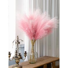 a vase filled with pink feathers on top of a wooden table