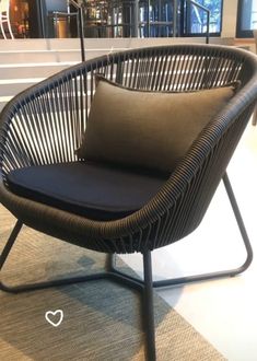 a wicker chair with a black cushion on it