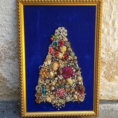 there is a framed picture with a christmas tree made out of beads and other things