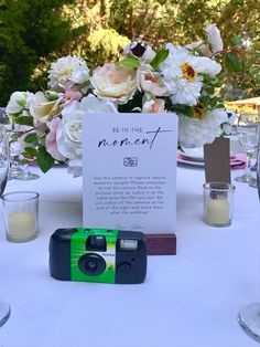 a camera sitting on top of a table next to a sign that says be in the moment