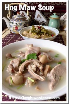 there is a bowl of soup with meat and vegetables on the table next to it