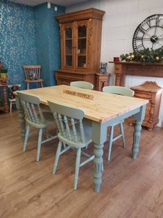 a dining room table with chairs and a clock on the wall in the back ground