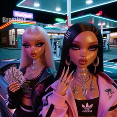 two dolls are standing next to each other in front of a neon lit gas station