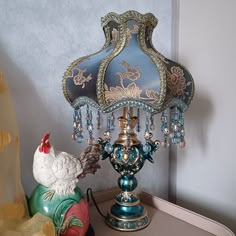 a blue lamp sitting on top of a table next to a chicken figurine