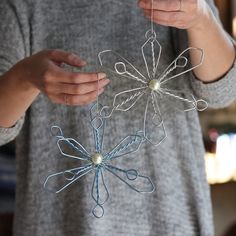 a woman is holding an ornament made out of wire and string, with one hand