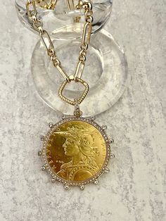 Beautiful reproduction vintage coin pendant, French Madagascar coin in a bezel with cubic zirconia stones. The bale attached to the coin is also encrusted with CZ stones. The coin is 22k gold plated and elegantly hangs from a multi link gold plated brass chain and a rope design spring lock clasp. The spring lock closure not only makes it easy to open and close the necklace for those with difficulty but adds to the creativity of the jewelry piece. Please see photograph of how to open the clasp. W Elegant Hallmarked Coin Necklace, Diamond Coin Pendant Medallion Jewelry, Luxury Yellow Gold Coin Medallion Necklace, Luxury Gold Coin Medallion Necklace, Antique Gold Necklace With Diamond Accents, Luxury Gold Plated Coin Necklace, Diamond Coin Pendant Jewelry, Luxury Gold Coin Pendant Necklace, Anniversary Medallion Necklace With Coin Pendant