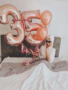 a person laying on a bed with some balloons in the shape of numbers and letters