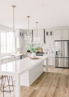 a large kitchen with white cabinets and counter tops, along with an island in the middle