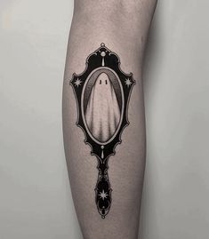 a black and white photo of a ghost in a mirror tattoo on the right leg