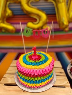 a colorful birthday cake sitting on top of a wooden table