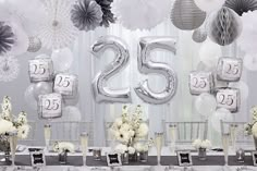 the table is set up with silver and white decorations for an elegant 25th birthday party