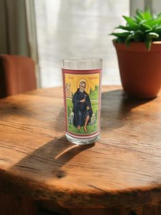 a candle sitting on top of a wooden table next to a potted plant