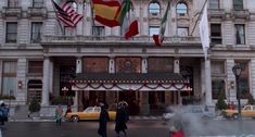 people walking in front of a building with flags on it