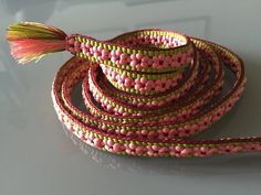 a pink and green beaded belt with a tassel on it's end