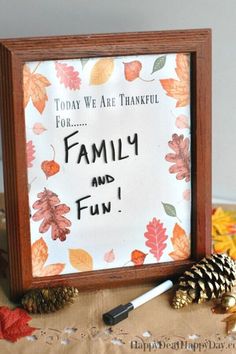 a family and fun sign in a frame with pine cones on the table next to it