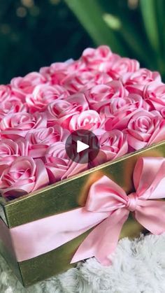 a box filled with pink roses sitting on top of a white blanket