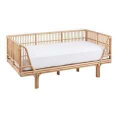 a bed made out of bamboo with white sheets on the top and bottom half, in front of a white background