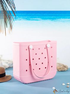 a pink tote bag sitting on top of a table next to a straw hat