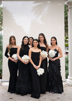 a group of women standing next to each other holding bouquets and posing for the camera