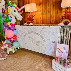 there is a table with balloons and an unicorn on it in the room that has wooden paneling