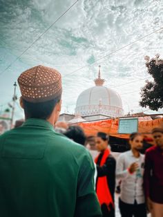 a man standing in front of a group of people wearing head coverings and looking up at the sky