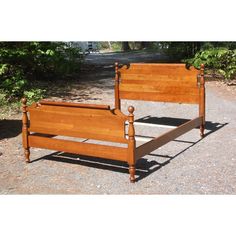 a wooden bed frame sitting on top of a gravel road