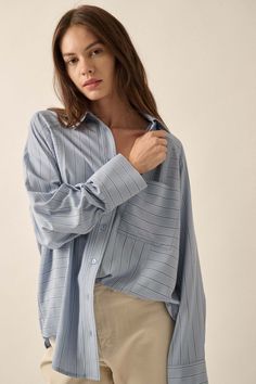 Striped button-down shirt. Collared neckline. Button front closure. Long raglan sleeves with buttoned cuffs. Chest pocket. Yoke back. Curved shirttail hem. Oversized fit. 100% Polyester. Imported. Designed in LA. Model wears size S. Blue Shirt With Roll-up Sleeves And Shirttail Hem, Blue Shirt With Placket And Shirttail Hem, Blue Blouse With Button Cuffs And Shirttail Hem, Light Blue Shirt With Placket For Spring, Light Blue Button-up Shirt With Placket, Light Blue Button-up Shirt With Pockets, Oversized Blue Button-up Blouse, Blue Shirt With Roll-up Sleeves For Everyday, Oversized Blue Shirt With Roll-up Sleeves