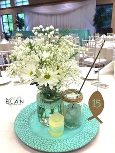 there is a vase with white flowers in it on the table at this wedding reception