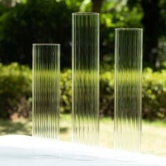 three tall glass vases sitting on top of a white table