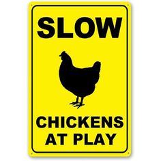 a yellow sign that says slow chickens at play with a black chicken in the center