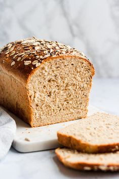 a loaf of bread sitting on top of a cutting board next to two slices of bread