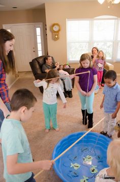 a group of young children playing with toys in a living room next to a woman