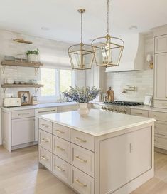 a large kitchen with white cabinets and an island in the middle is decorated with gold accents