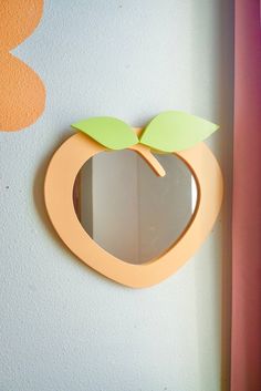 an apple shaped mirror mounted to the side of a wall