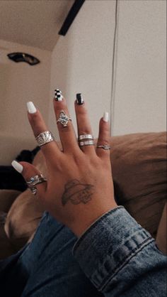 a woman's hand with several rings on it and her fingers in the air