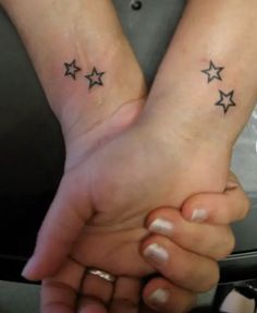 two people holding hands with stars tattooed on their wrists, one is black and the other is white