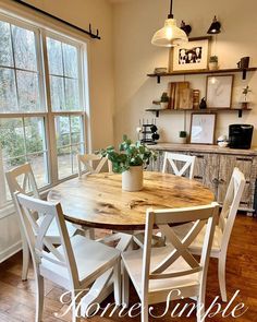 a dining room table with white chairs and a potted plant on top of it